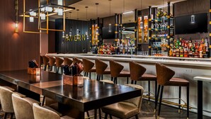 Un espace bar doté d’un long comptoir, de nombreux tabourets et d’une variété de bouteilles et de verres.