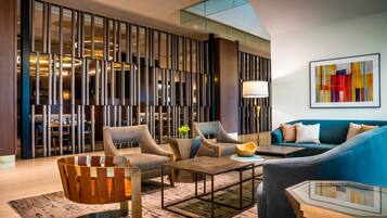 A modern living room with a sectional sofa, armchairs, a coffee table, and a decorative wall panel.