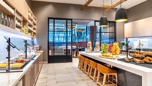 Une cuisine moderne avec un espace buffet, des tabourets de bar en bois et une vue sur l’intérieur.