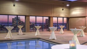 Une terrasse sur le toit, aménagée avec des tables pour les repas, offrant une vue sur les toits de la ville au crépuscule.