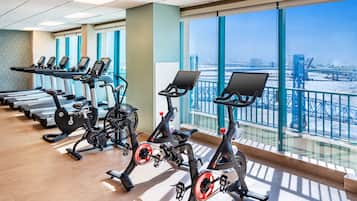 Un gimnasio con cintas de correr, bicicletas estáticas y elípticas.