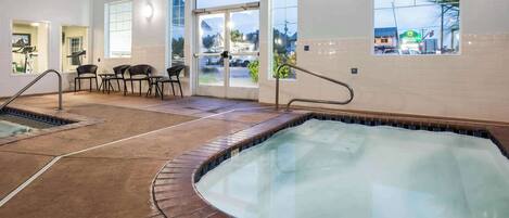 A spa area with a hot tub, seating area, and a view of the outside.