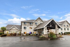 A multi-story hotel with a central entrance, a parking lot, and landscaped areas.