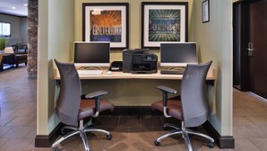 Un espace de travail comprenant deux bureaux, chacun équipé d’un écran d’ordinateur, d’un clavier et d’une imprimante. Il y a également deux chaises de bureau à roulettes.