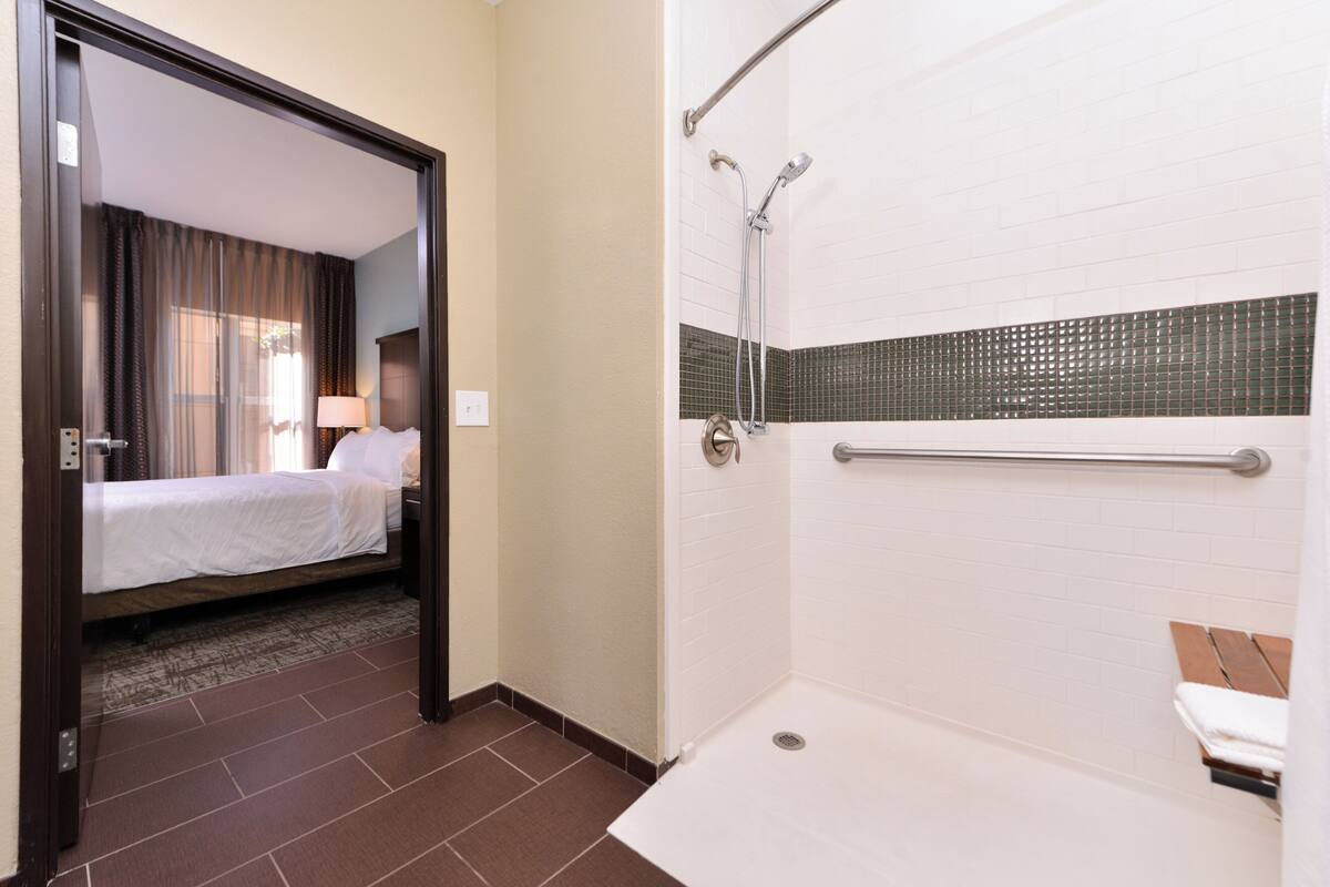 Een hotelkamer met een bed, een badkamer met een douche en een bank.
