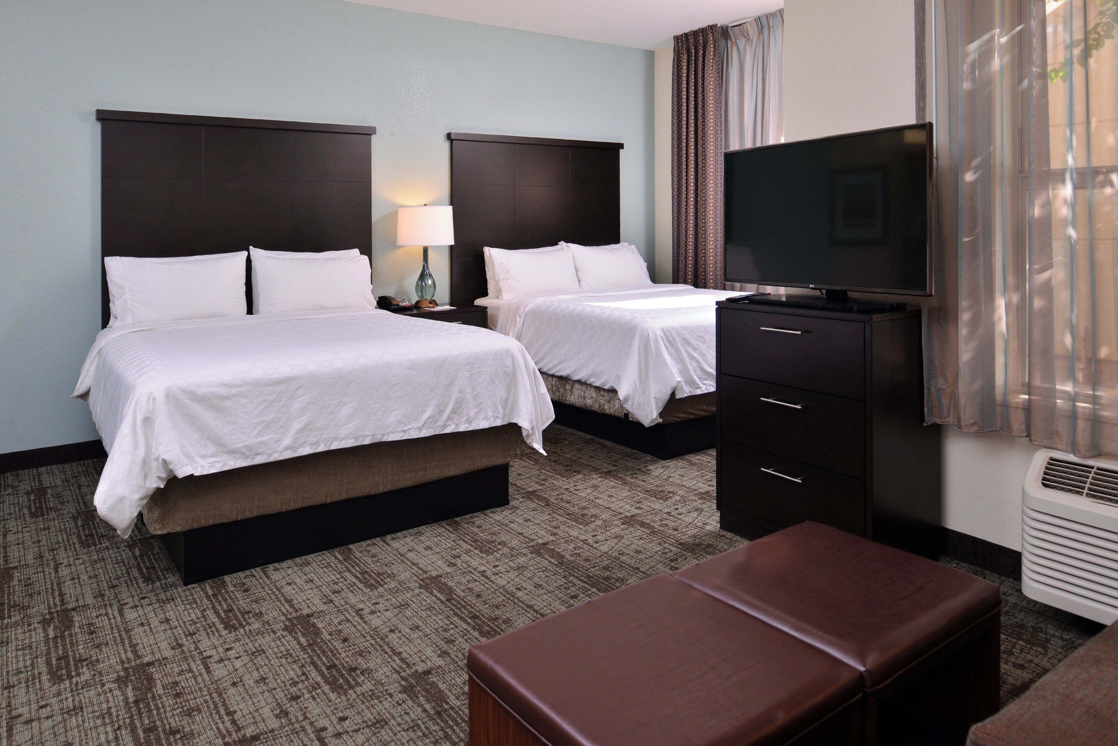 A hotel room with two beds, a TV, a desk, and a chair.