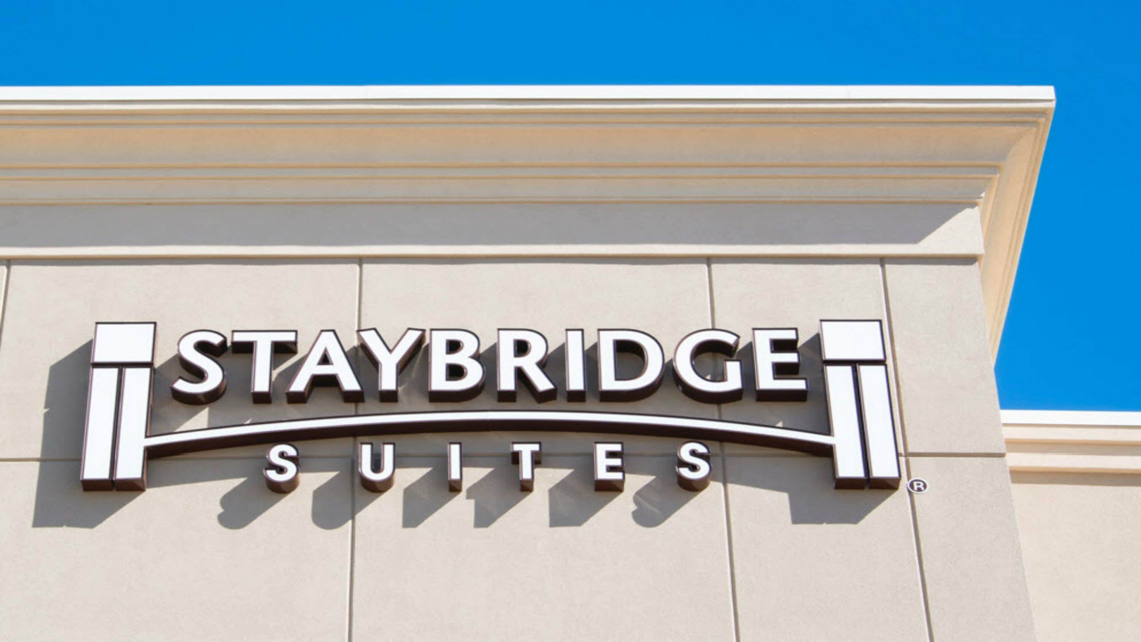 Schild für Staybridge Suites, im Hintergrund ein klarer, blauer Himmel.