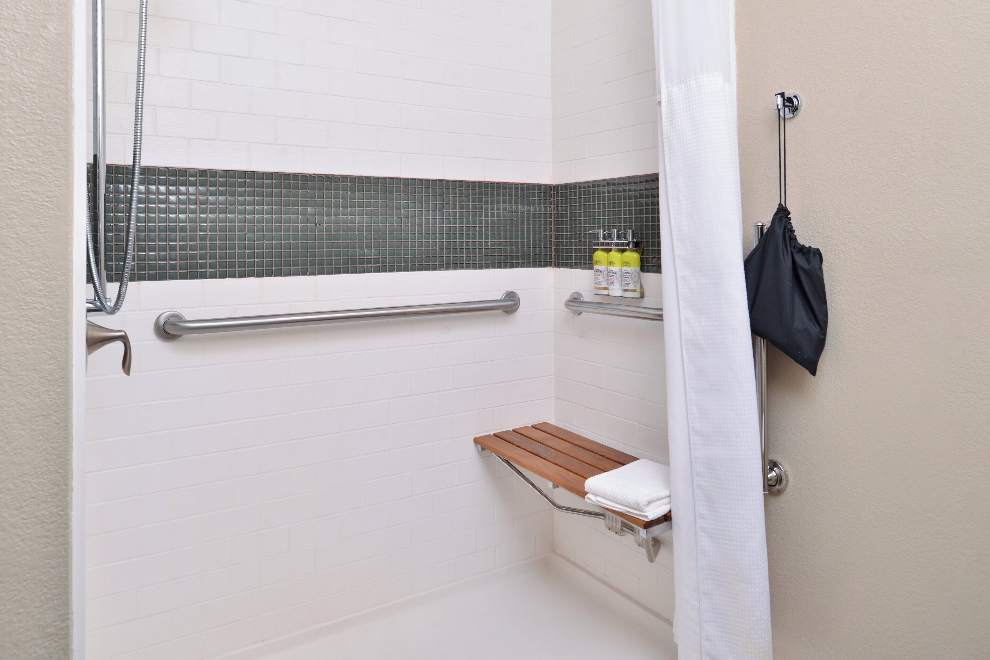 Een douche met een glazen deur, een houten plank en een handdoekhouder.