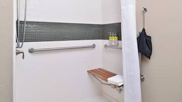 Een douche met een glazen deur, een houten plank en een handdoekhouder.