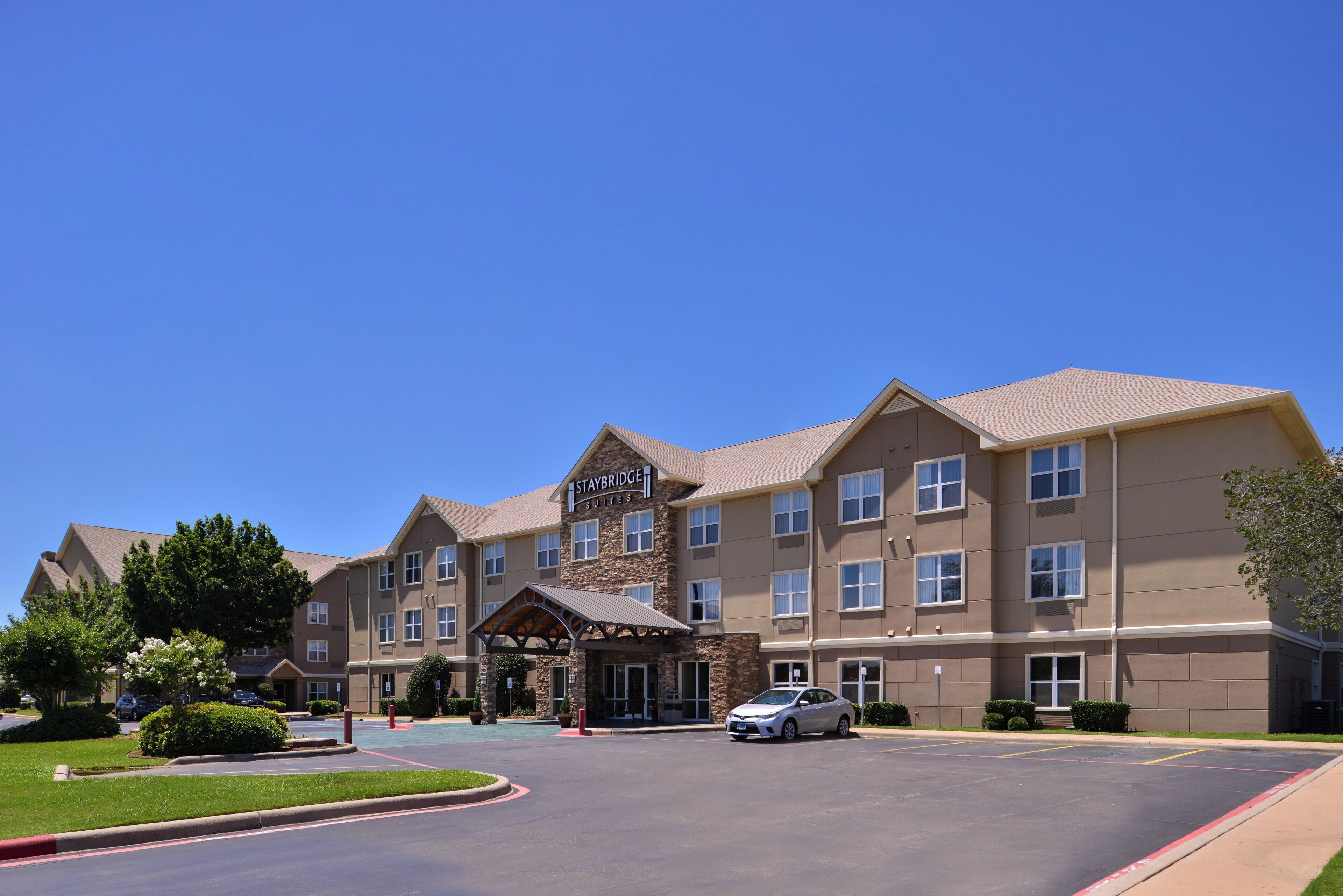 A Staybridge Suites hotel with a stone facade, multiple windows, and a covered entrance.