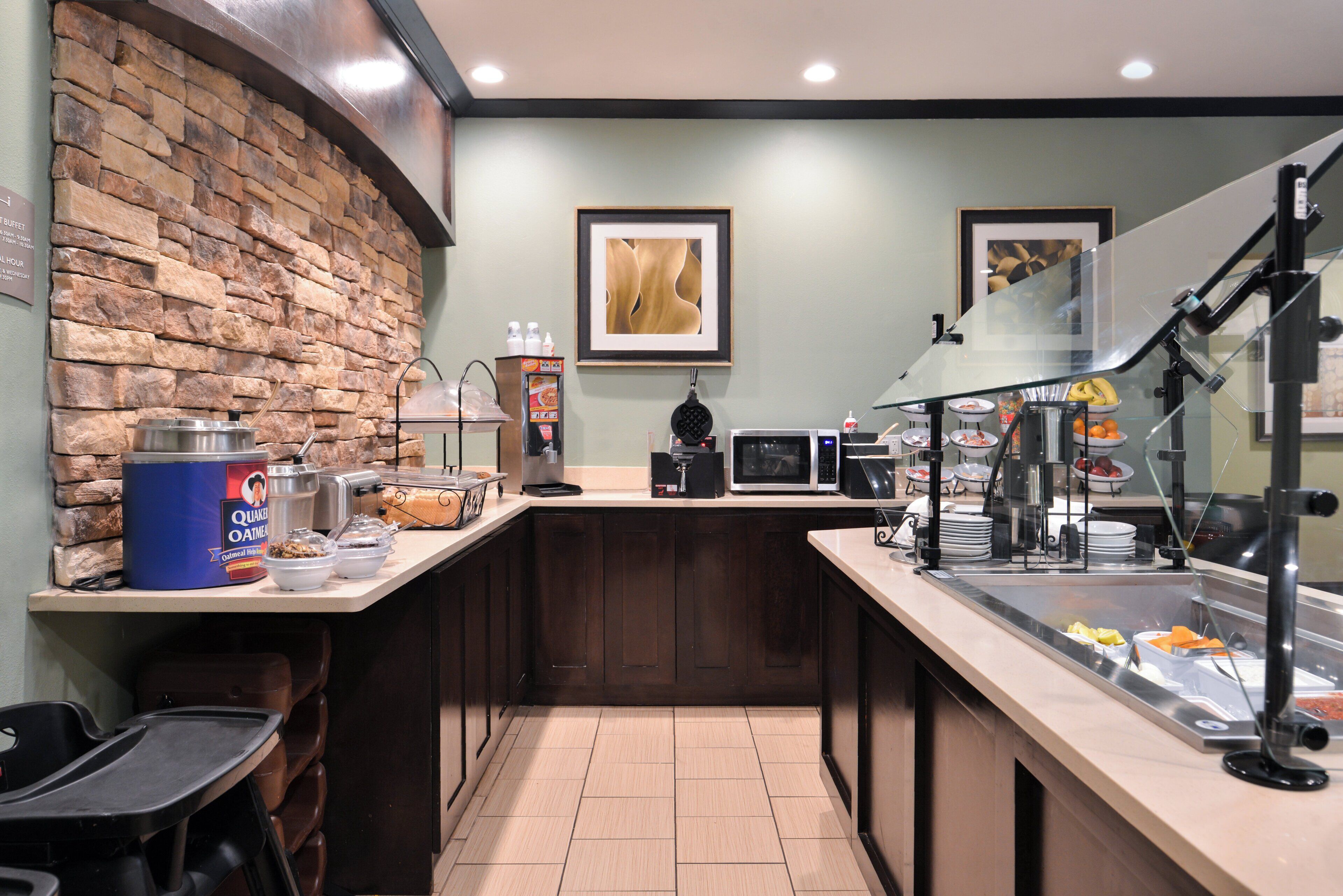 A breakfast bar with a stone wall, a coffee machine, and a microwave.