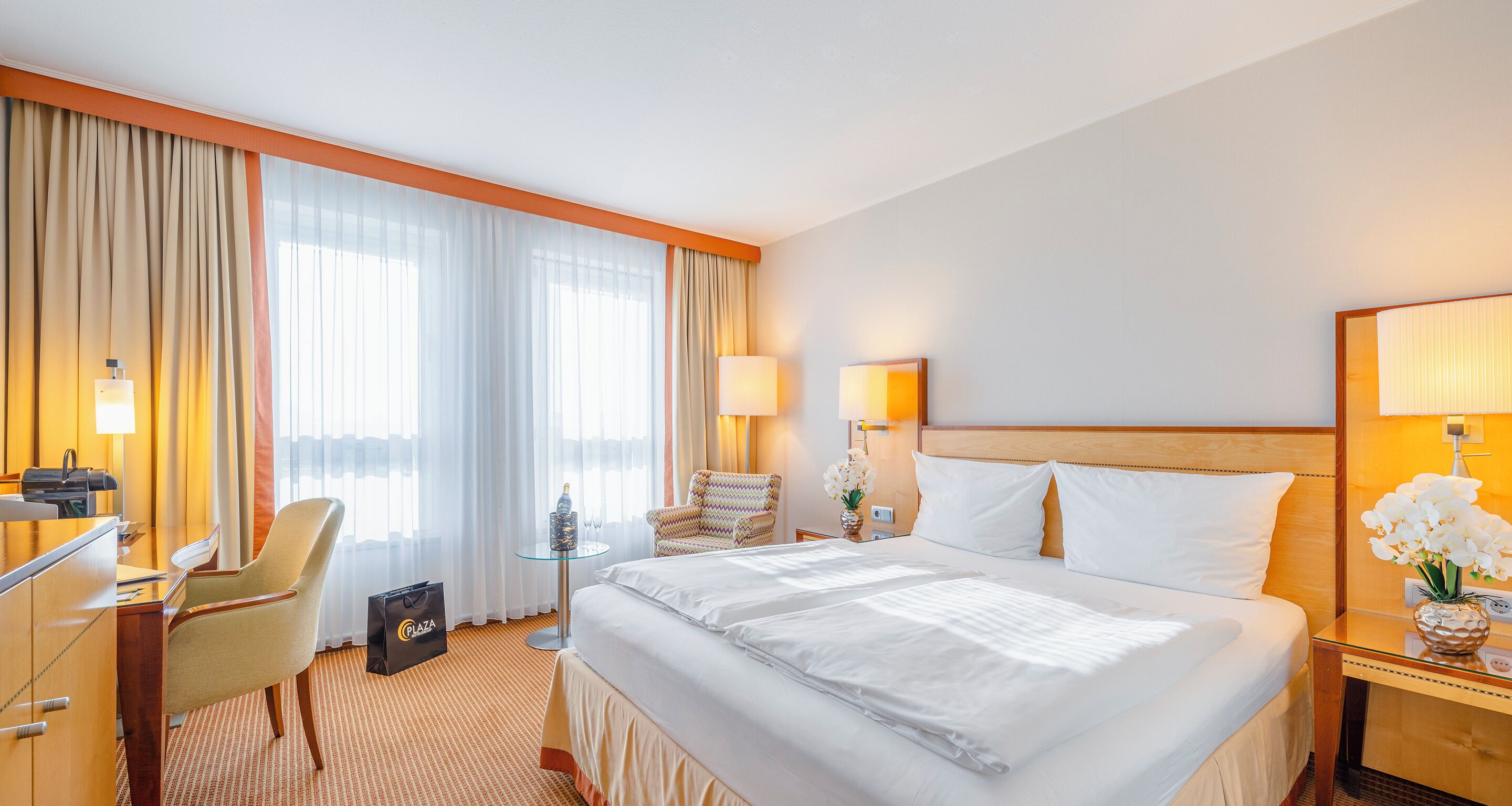 Une chambre d’hôtel avec un grand lit, un bureau, une chaise et une petite table avec une lampe.