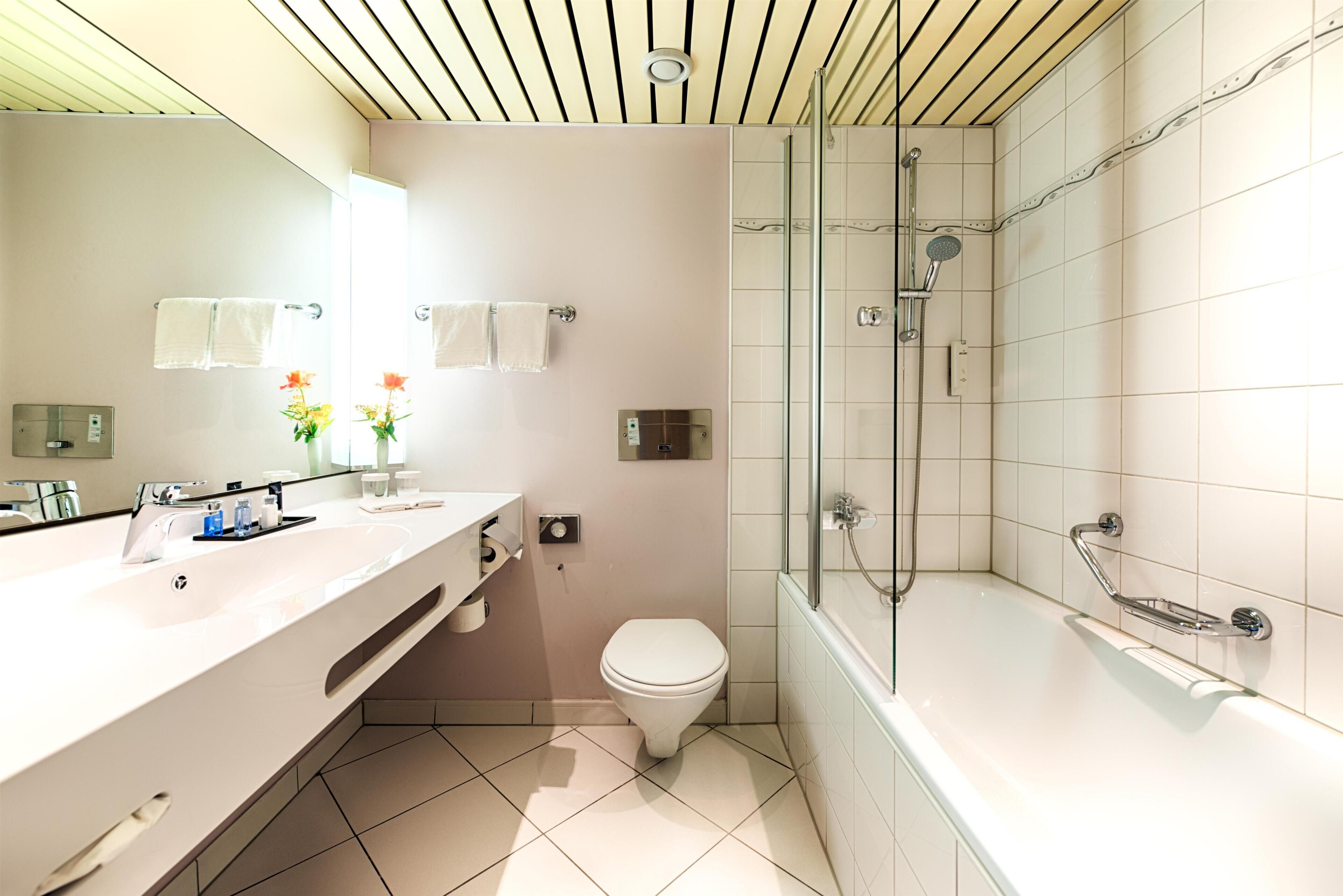 Un baño moderno con un lavamanos grande, inodoro y ducha con mampara de vidrio.