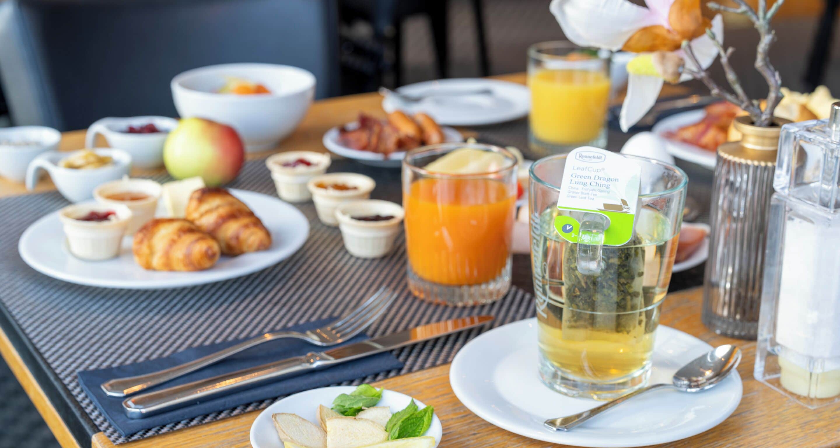 Et morgenbord med croissanter, frugt, te og juice.