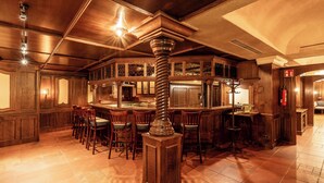 A bar area with wooden furniture, a central column, and a tiled floor.