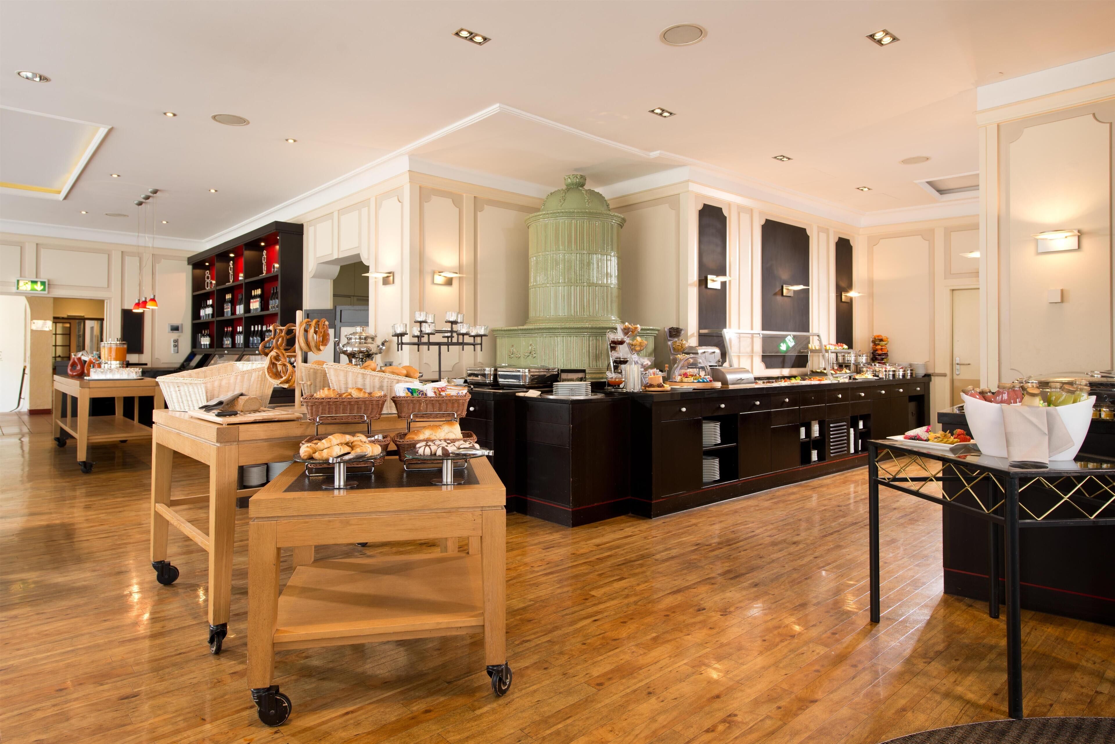 A spacious hotel lobby with a buffet area, wooden flooring, and a large green decorative piece.