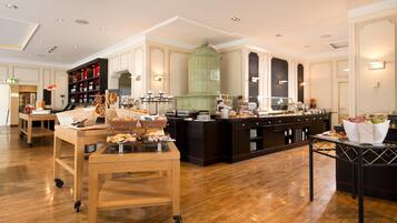 A spacious hotel lobby with a buffet area, wooden flooring, and a large green decorative piece.