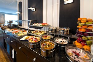 Un bufé con diversas frutas, verduras y postres.
