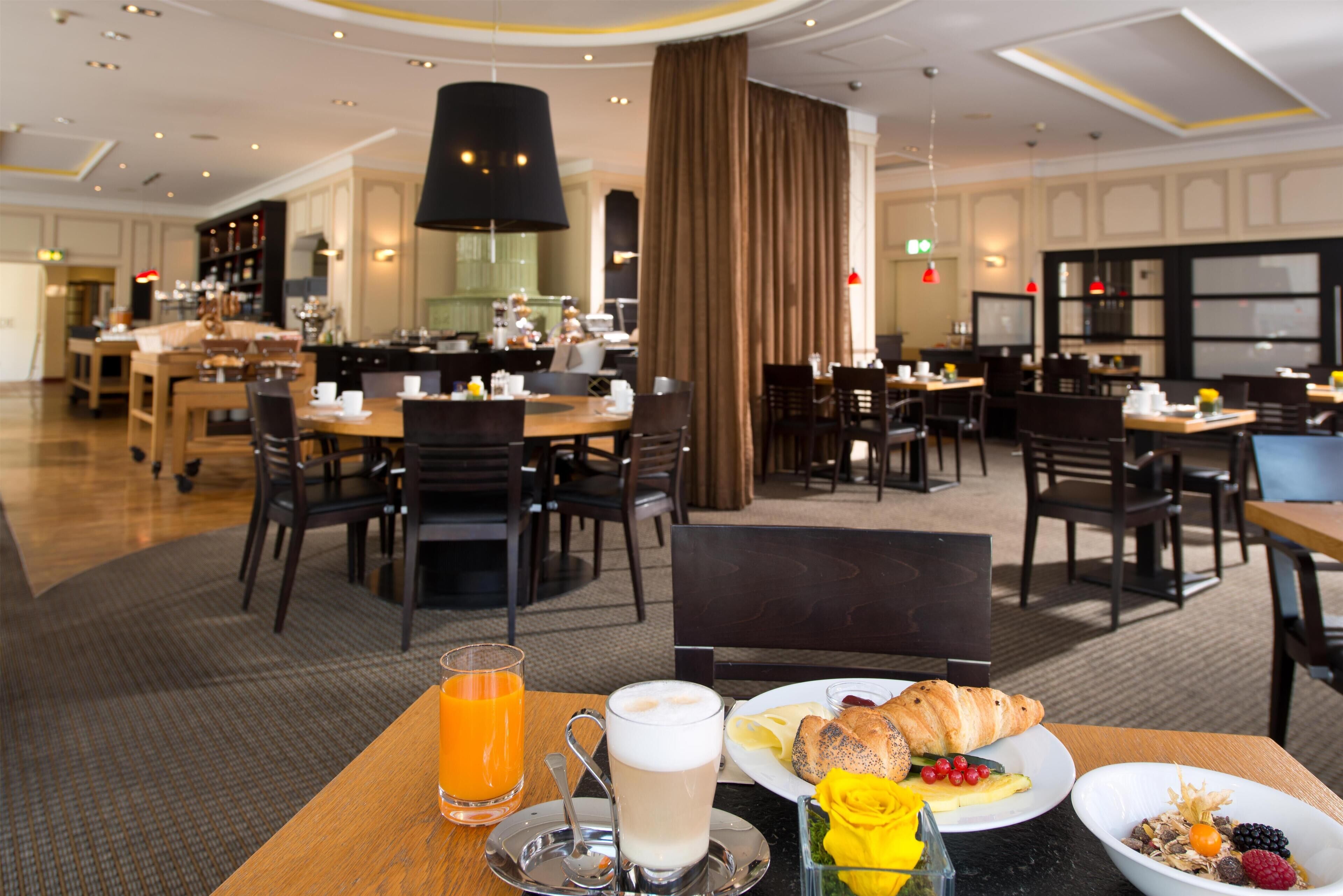 A hotel dining area with multiple tables and chairs, a coffee station, and a buffet in the background.