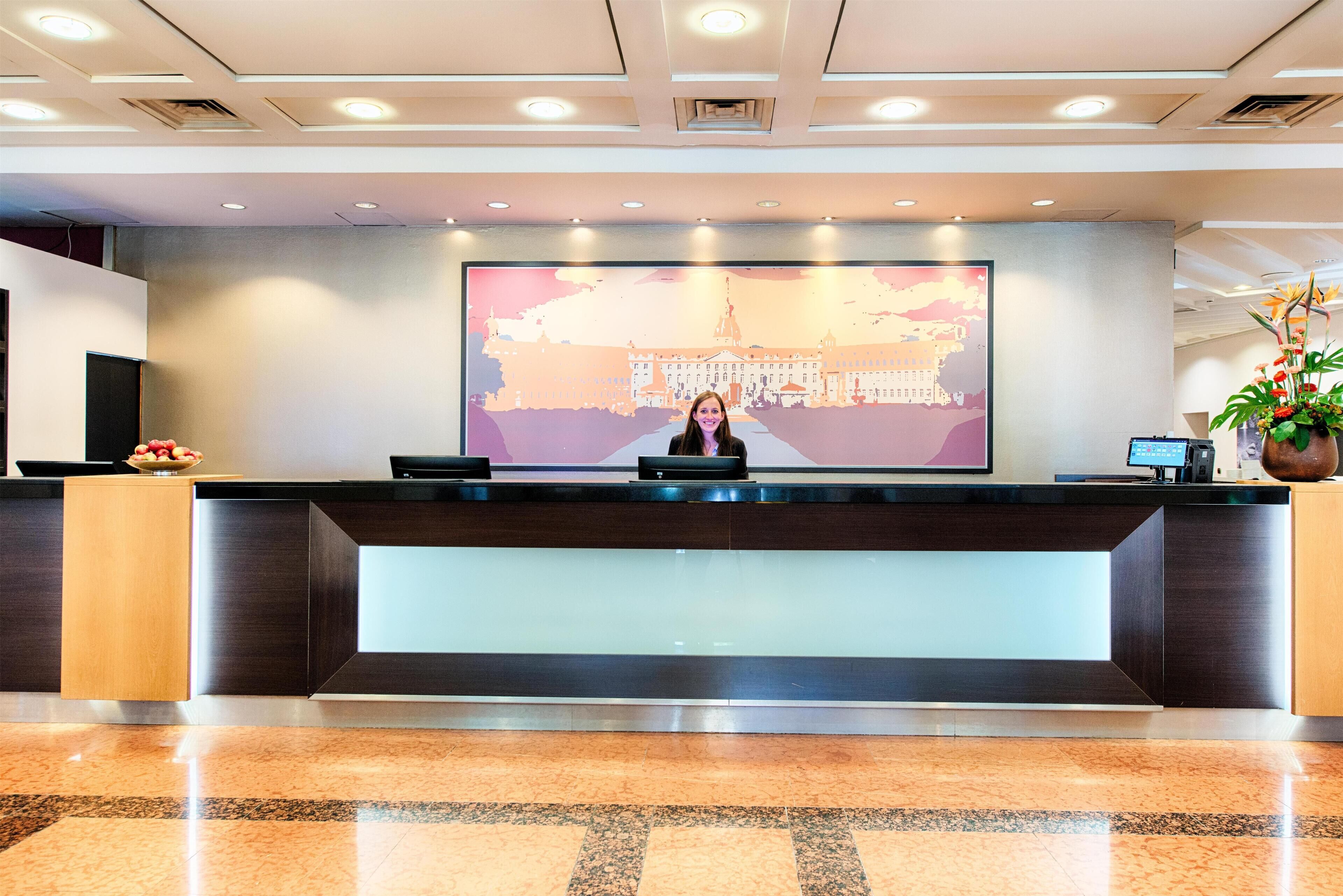 A modern hotel reception desk with a large digital screen displaying a cityscape.