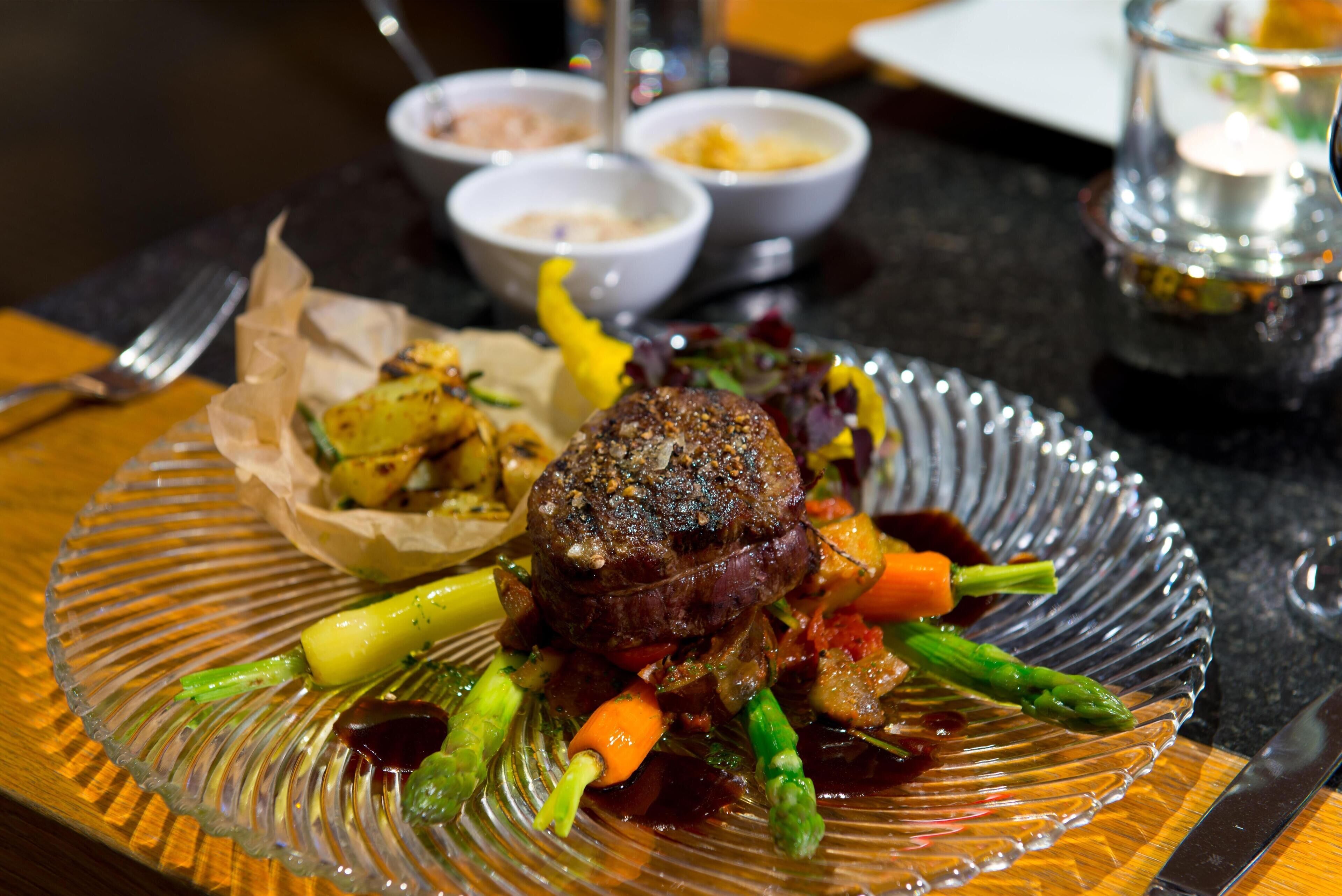 Een bord eten met een steak, groenten en saus.