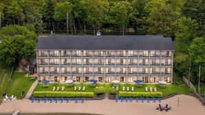 A multi-story hotel with a poolside area, outdoor seating, and a view of the water.