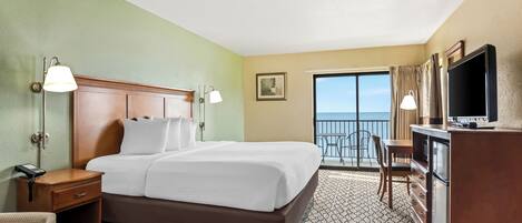 A hotel room with a bed, bedside lamps, a desk with a telephone, a dresser, a television, and a balcony with a view of the sky.