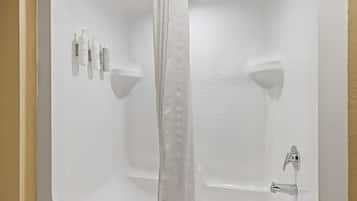 A white bathtub with a shower curtain, a handheld showerhead, and a set of toiletries on the wall.