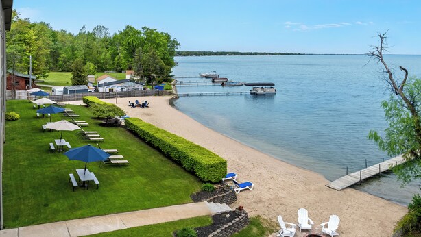 A lakeside property with a grassy lawn, outdoor seating, and a dock.