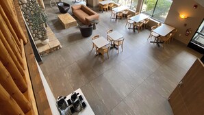 A spacious living area with a stone wall, a fireplace, a sofa, and a dining area with multiple tables and chairs.