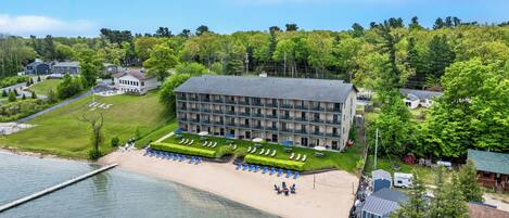 Ein Hotel mit Strand, Pool und bewaldetem Hügel – Luftaufnahme.