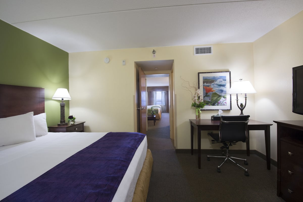 Une chambre d’hôtel avec un grand lit, un bureau, une chaise et une lampe de bureau.