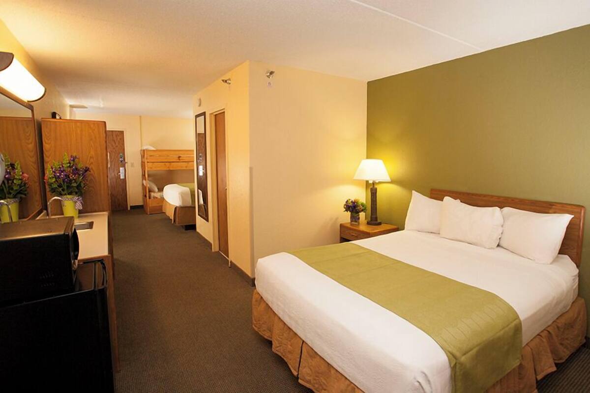 Une chambre d’hôtel comprenant un lit, une table de chevet, une lampe et un bureau avec une chaise.