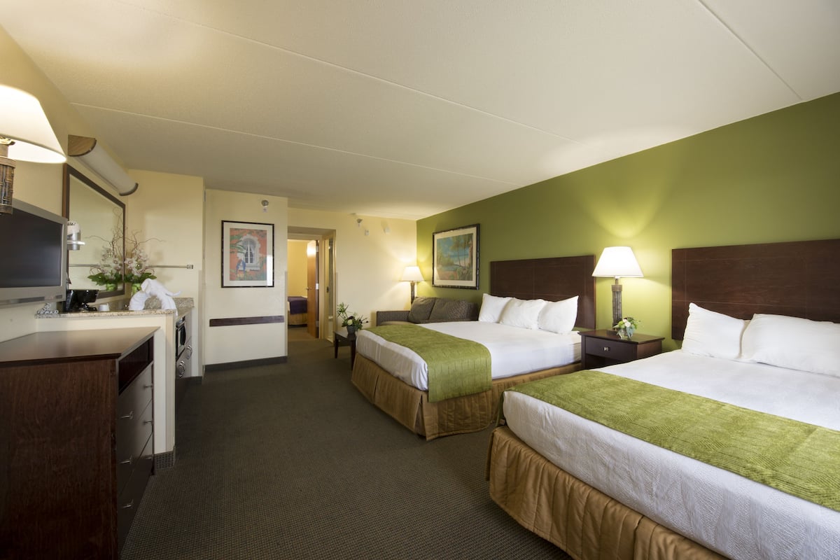 Une chambre d’hôtel avec deux lits, un bureau, une chaise et un téléviseur.