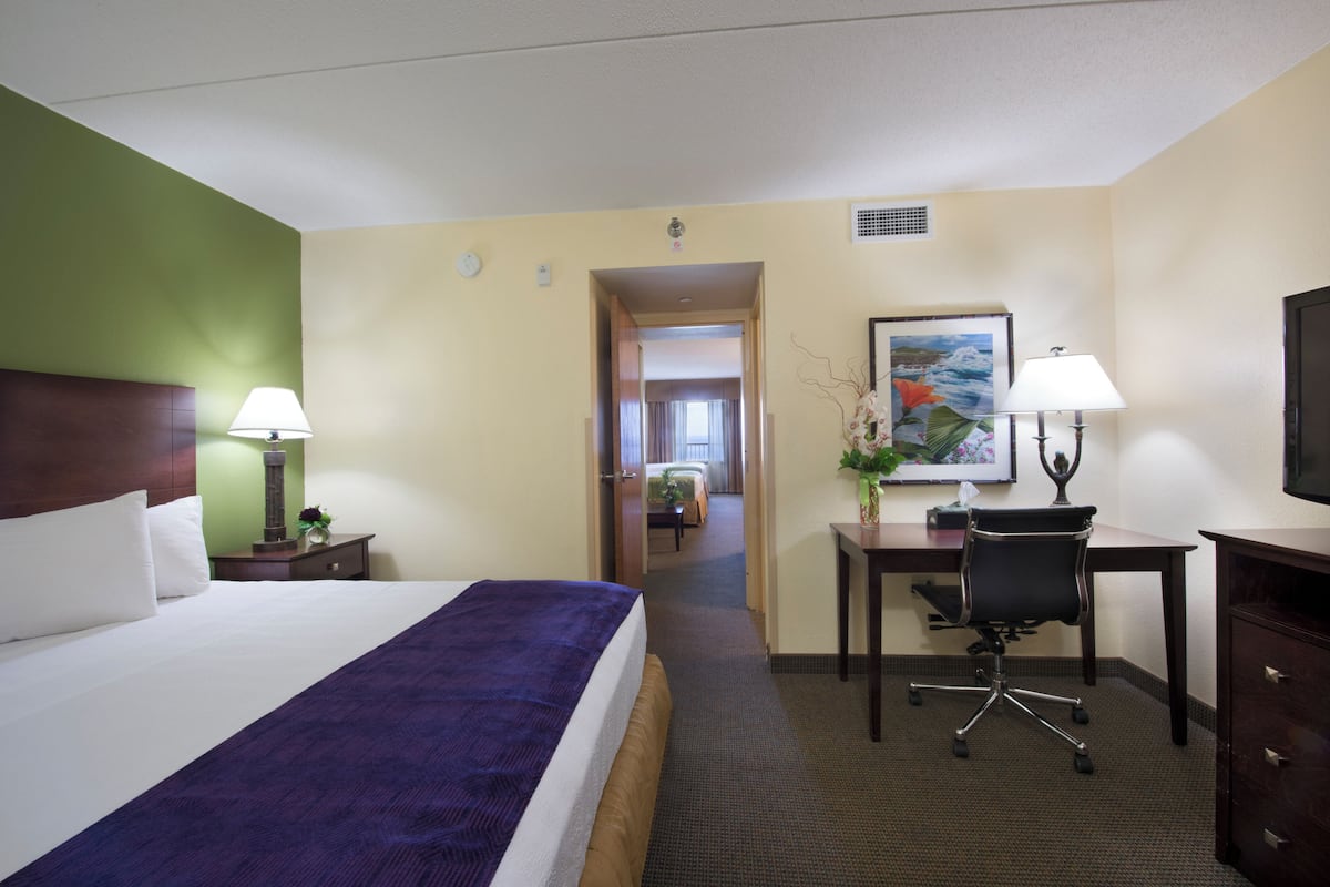 Une chambre d’hôtel avec un lit, un bureau, une chaise et un tableau au mur.