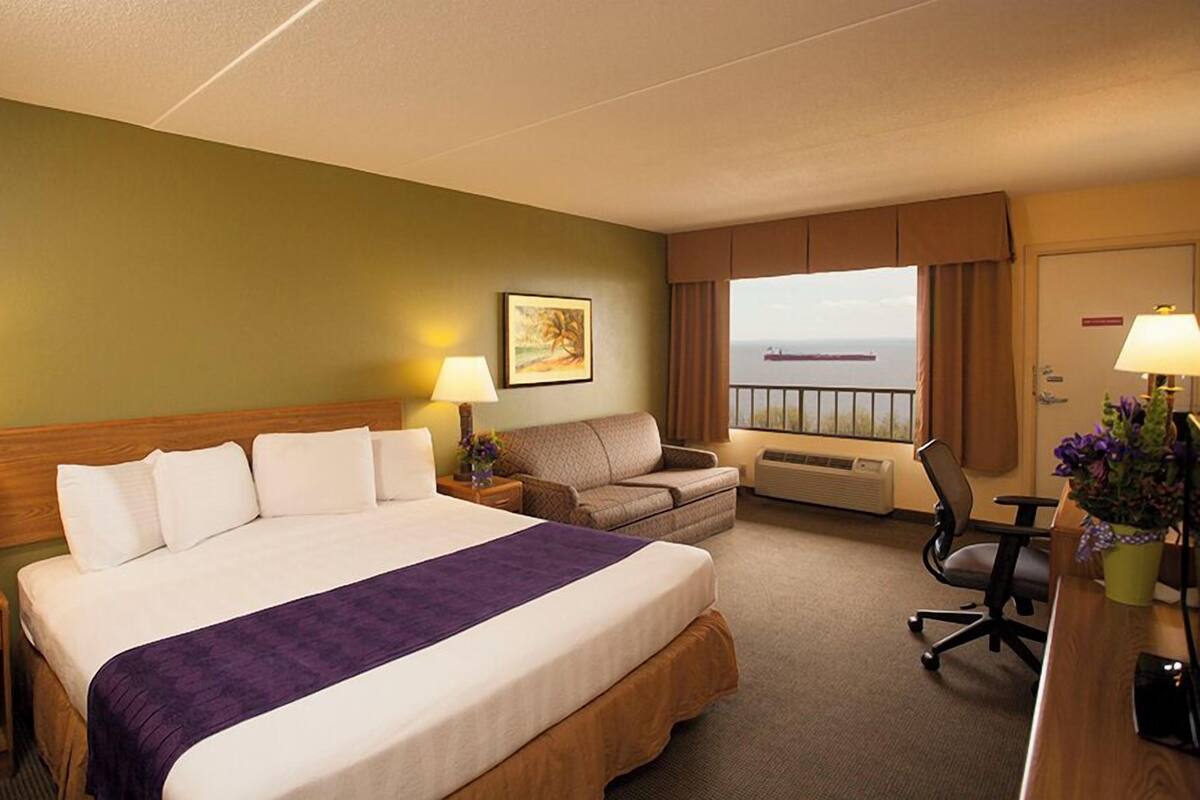 Une chambre d’hôtel avec un grand lit, un canapé, un bureau et une vue sur la mer.
