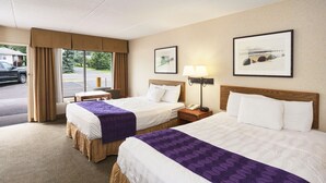 Ein Hotelzimmer mit zwei Betten, einem Schreibtisch, einem Stuhl, einer Lampe und einem Fenster mit Vorhängen.