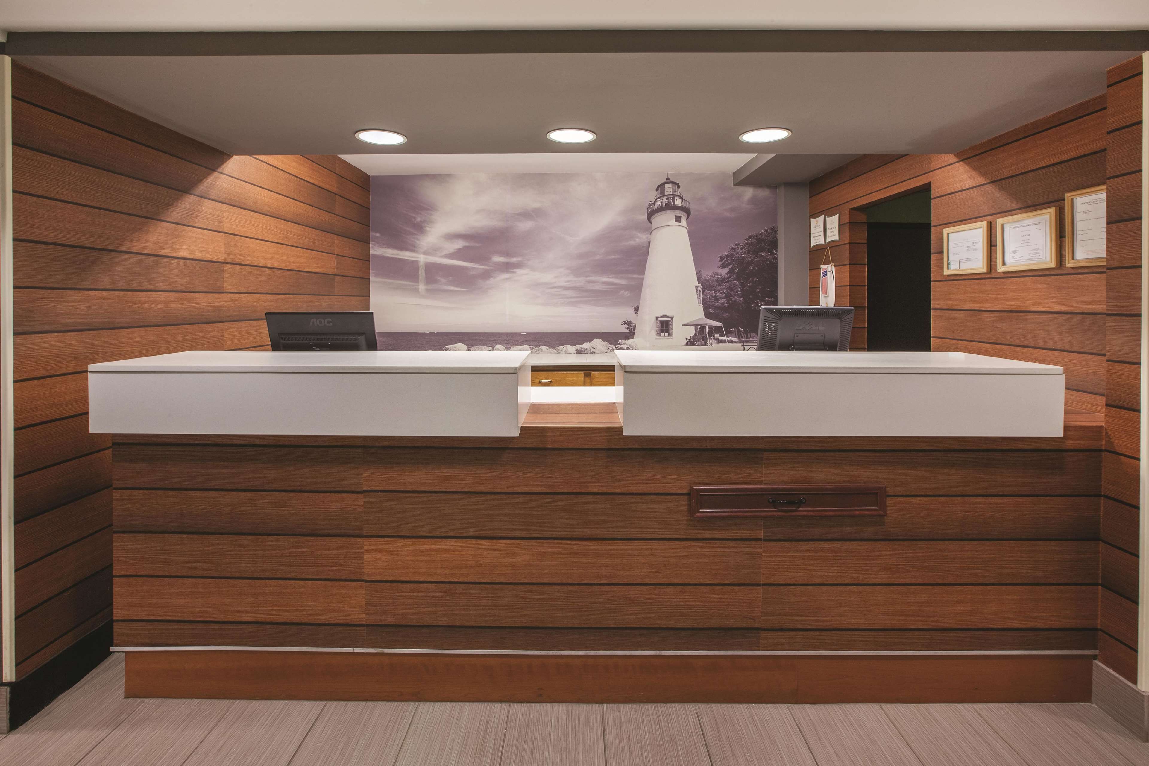 A reception desk with a wooden panel design, a laptop on the counter, and framed certificates on the wall.