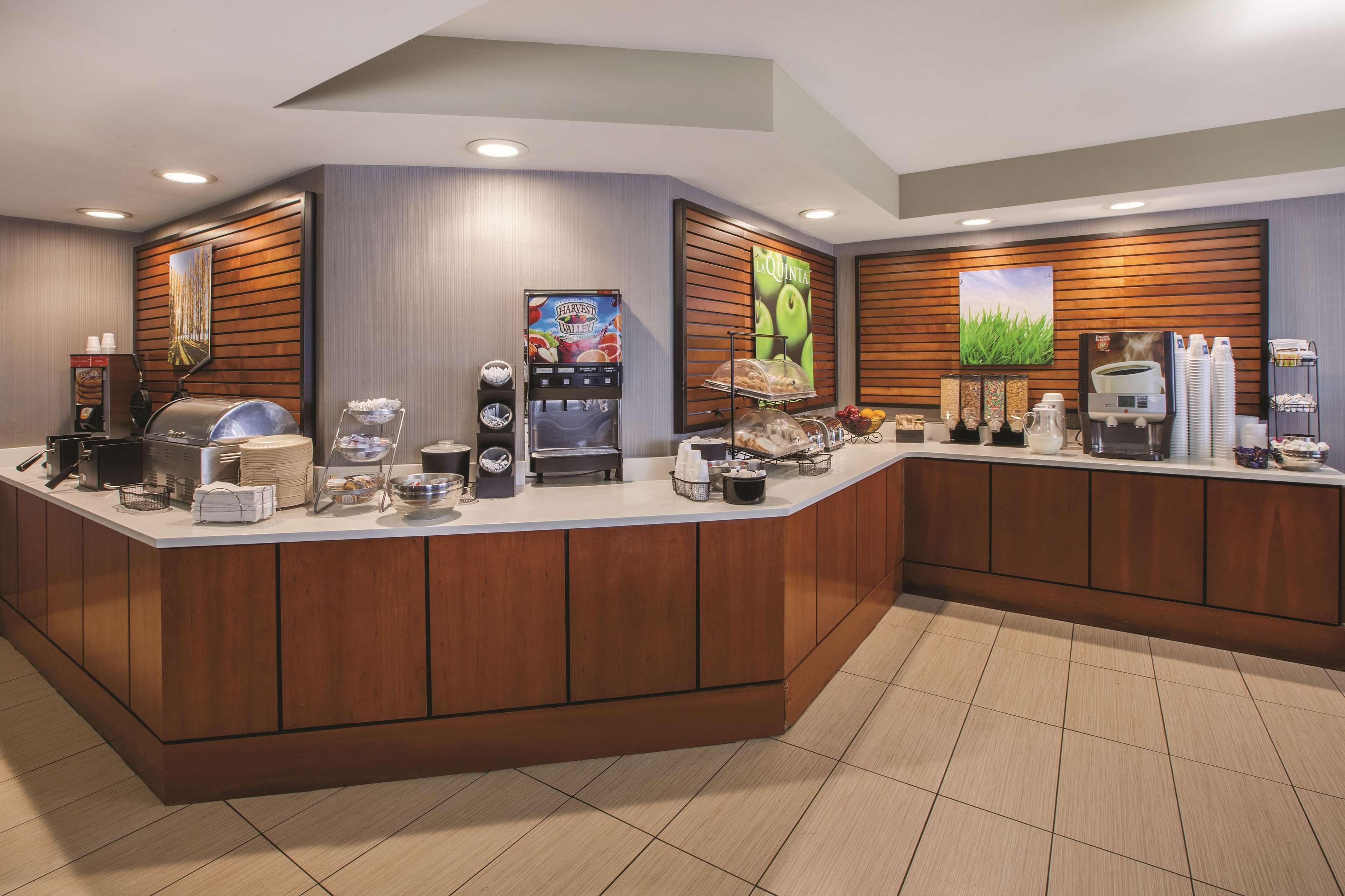 Ein Hotel-Empfangsbereich mit Holztresen, Kaffeeautomaten und einer Obstauslage.