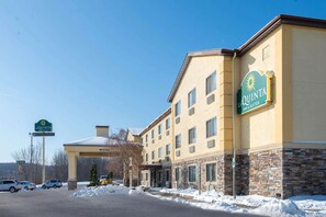 A La Quinta Inn & Suites building with a snow-covered parking lot and clear blue sky. - La Quinta Inn & Suites by Wyndham Erie (Erie)