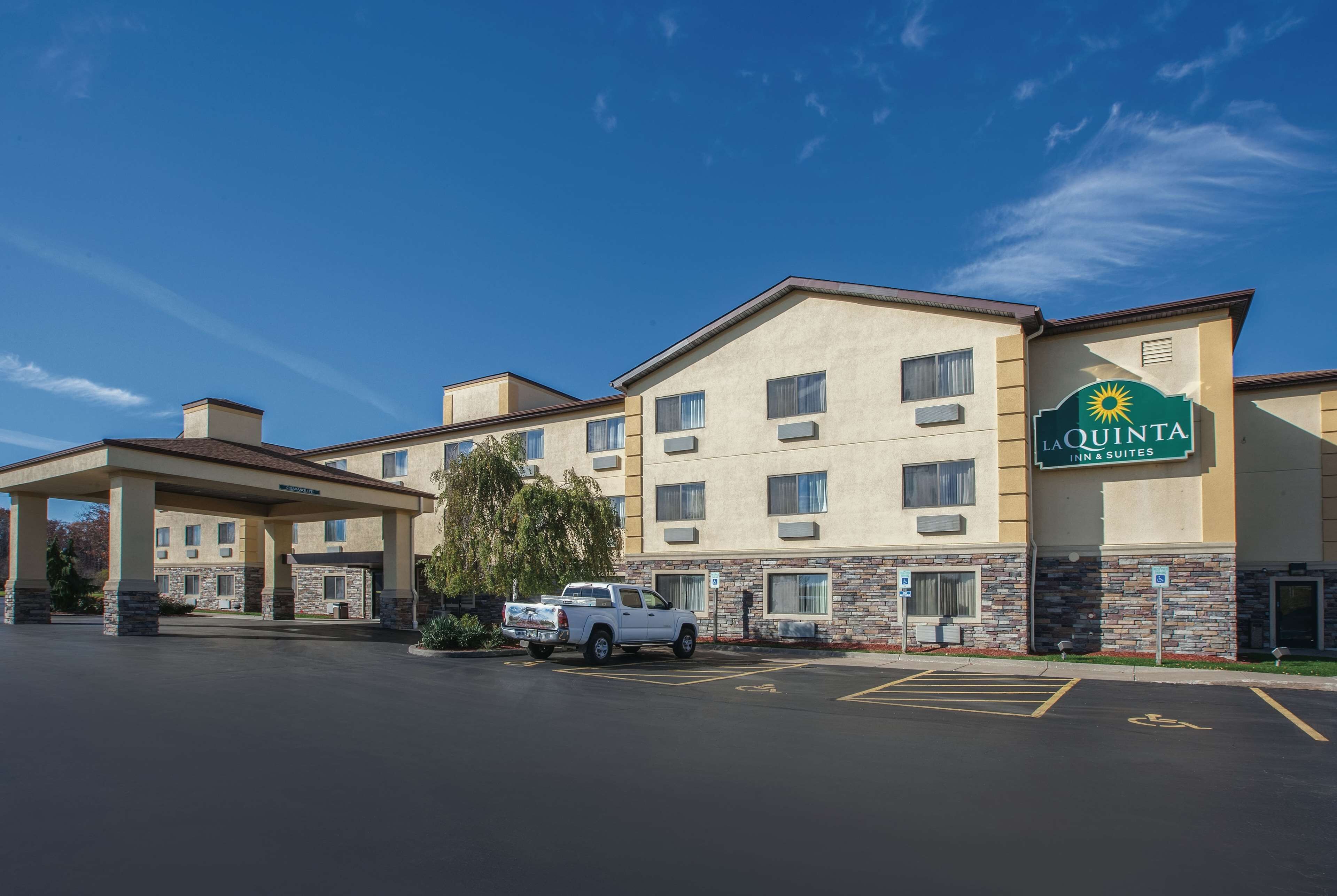 A La Quinta Inn & Suites building with a covered parking area and a white pickup truck parked in front.