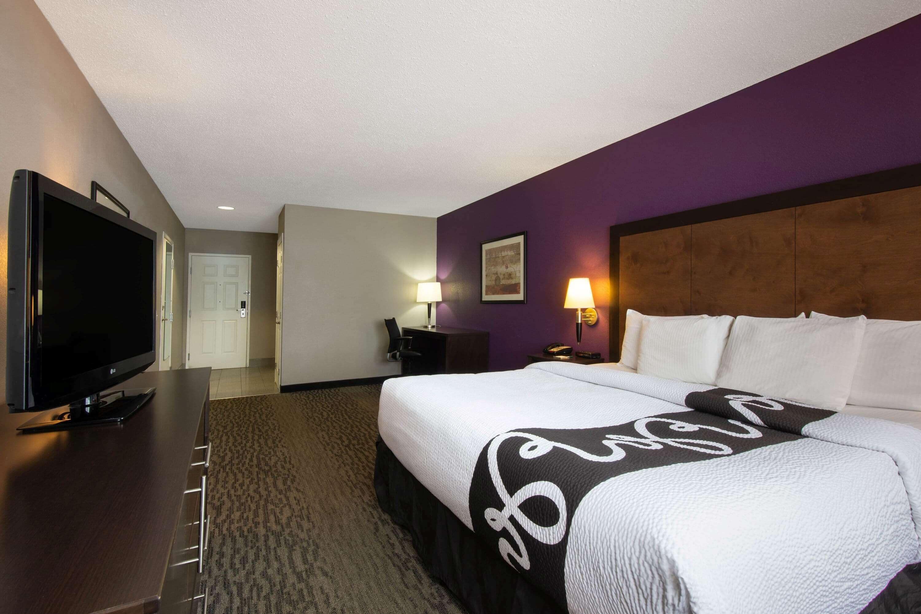 Una habitación de hotel con cama, televisión, escritorio y lámpara.