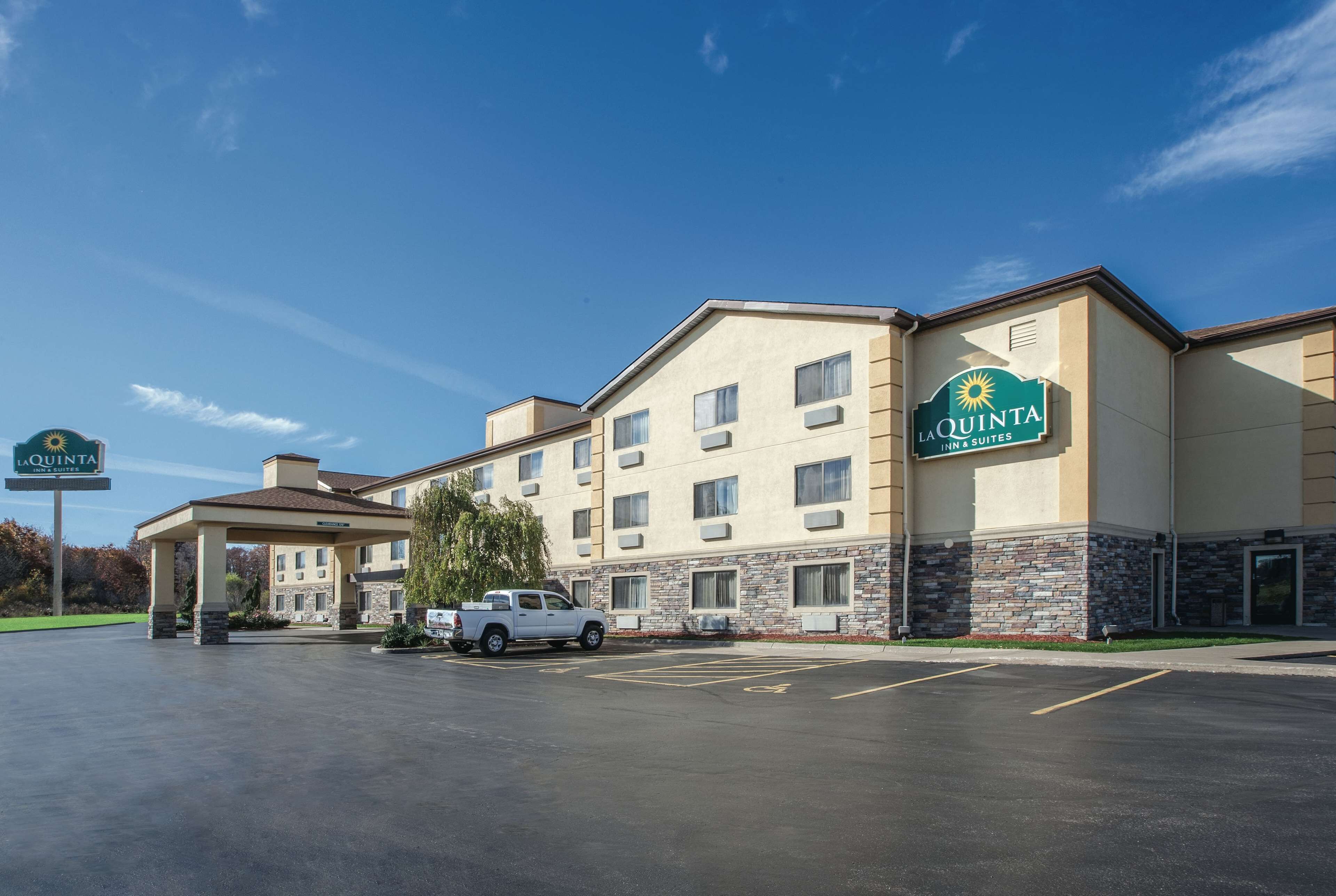 A La Quinta Inn & Suites hotel with a parking lot, a covered entrance, and a white pickup truck parked in front.