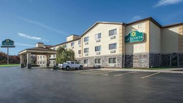 A La Quinta Inn & Suites hotel with a parking lot, a covered entrance, and a white pickup truck parked in front.