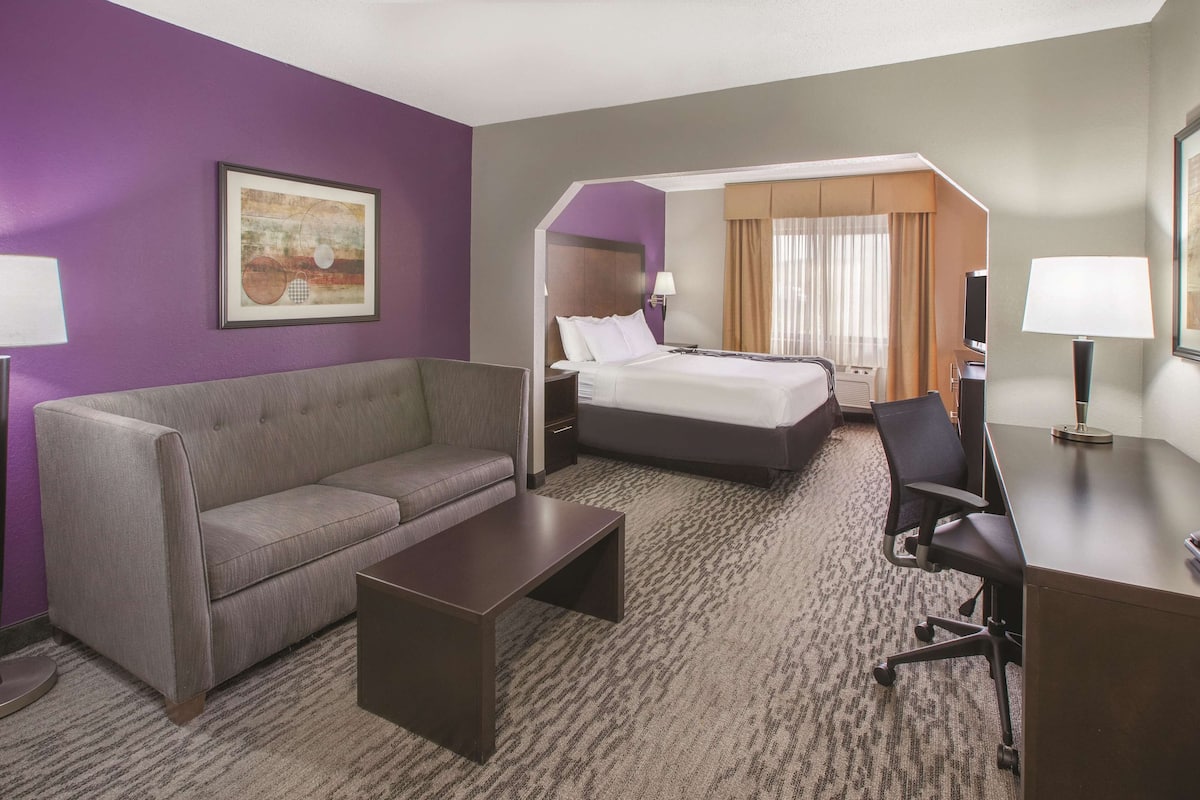 A hotel room with a bed, a sofa, a desk, and a chair.