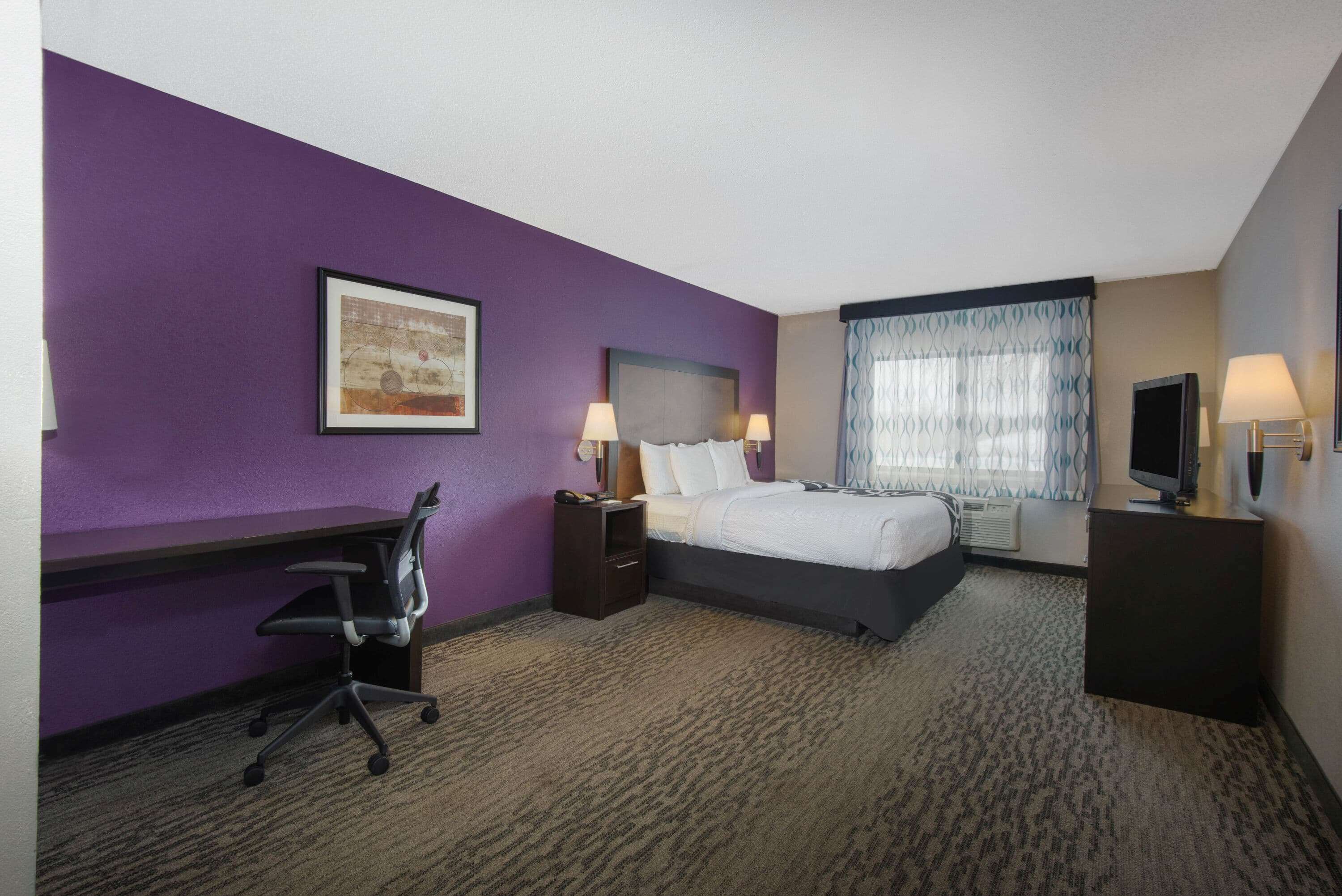 Une chambre d’hôtel équipée d’un lit, d’un bureau, d’une chaise et d’un téléviseur.