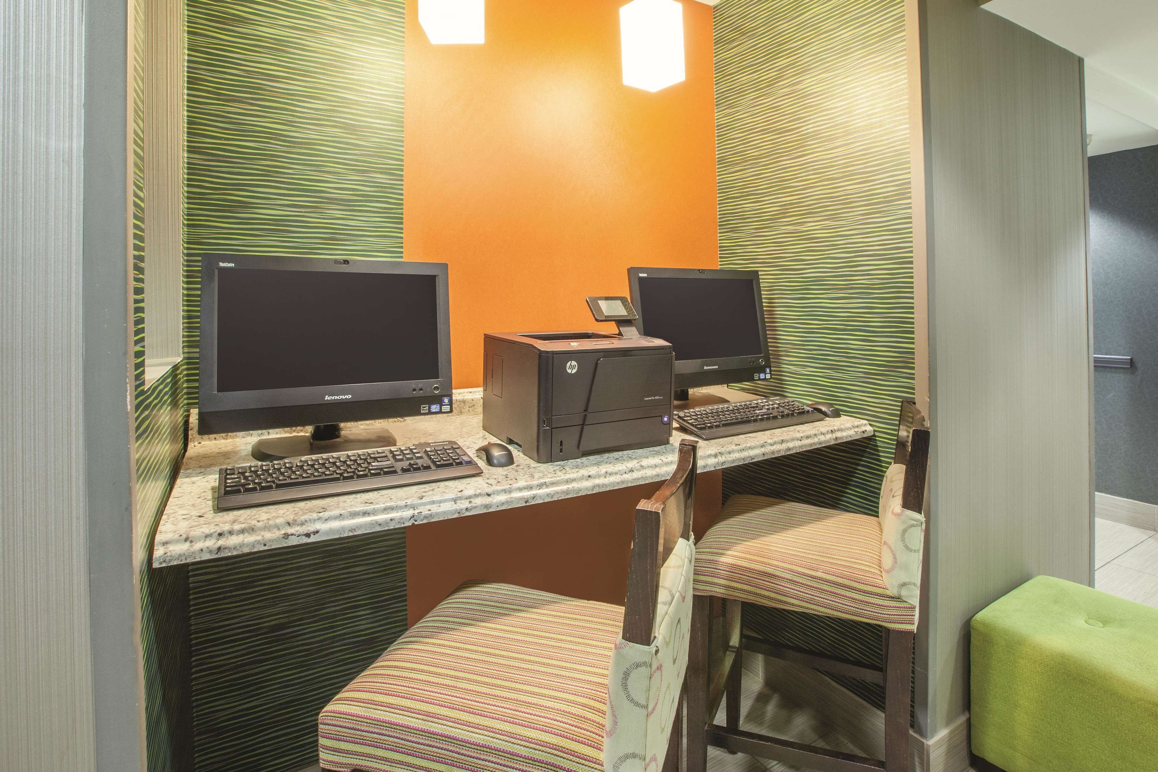 A workspace with two HP desktop computers, a keyboard, and a mouse on a marble countertop.