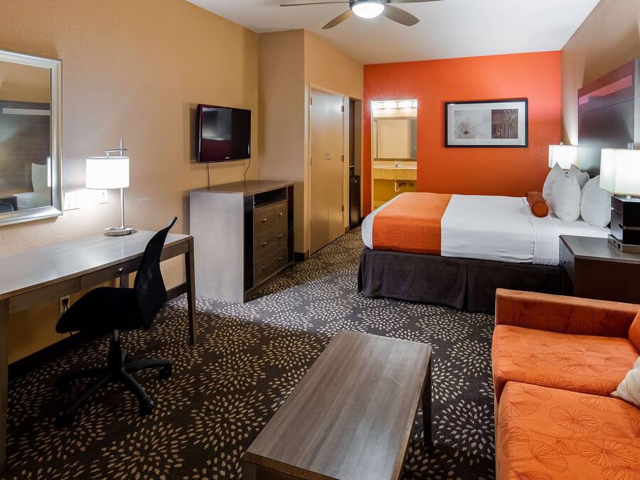 A hotel room with a desk, chair, bed, and a sofa.