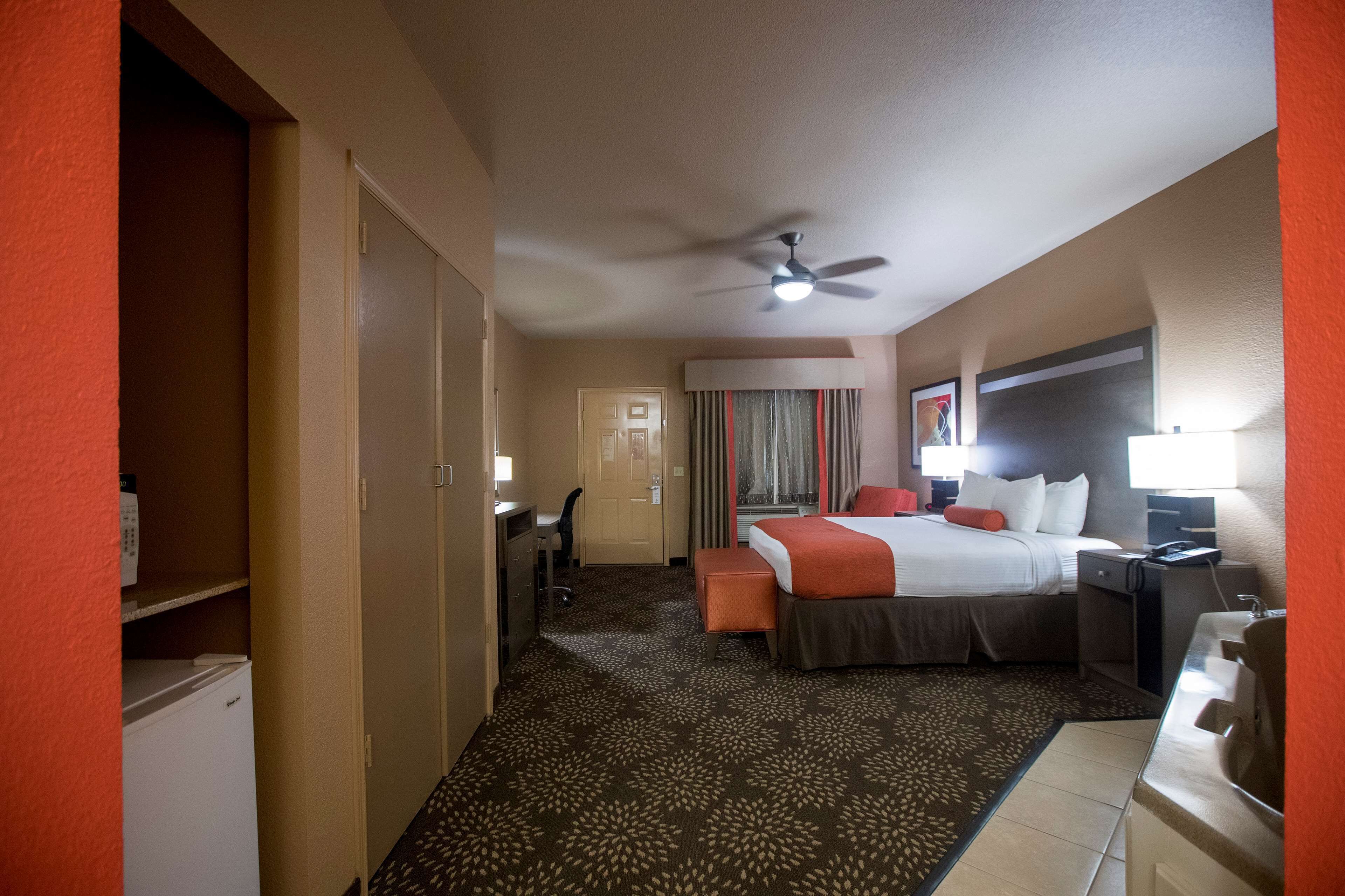 A hotel room with a bed, desk, chair, and a ceiling fan.