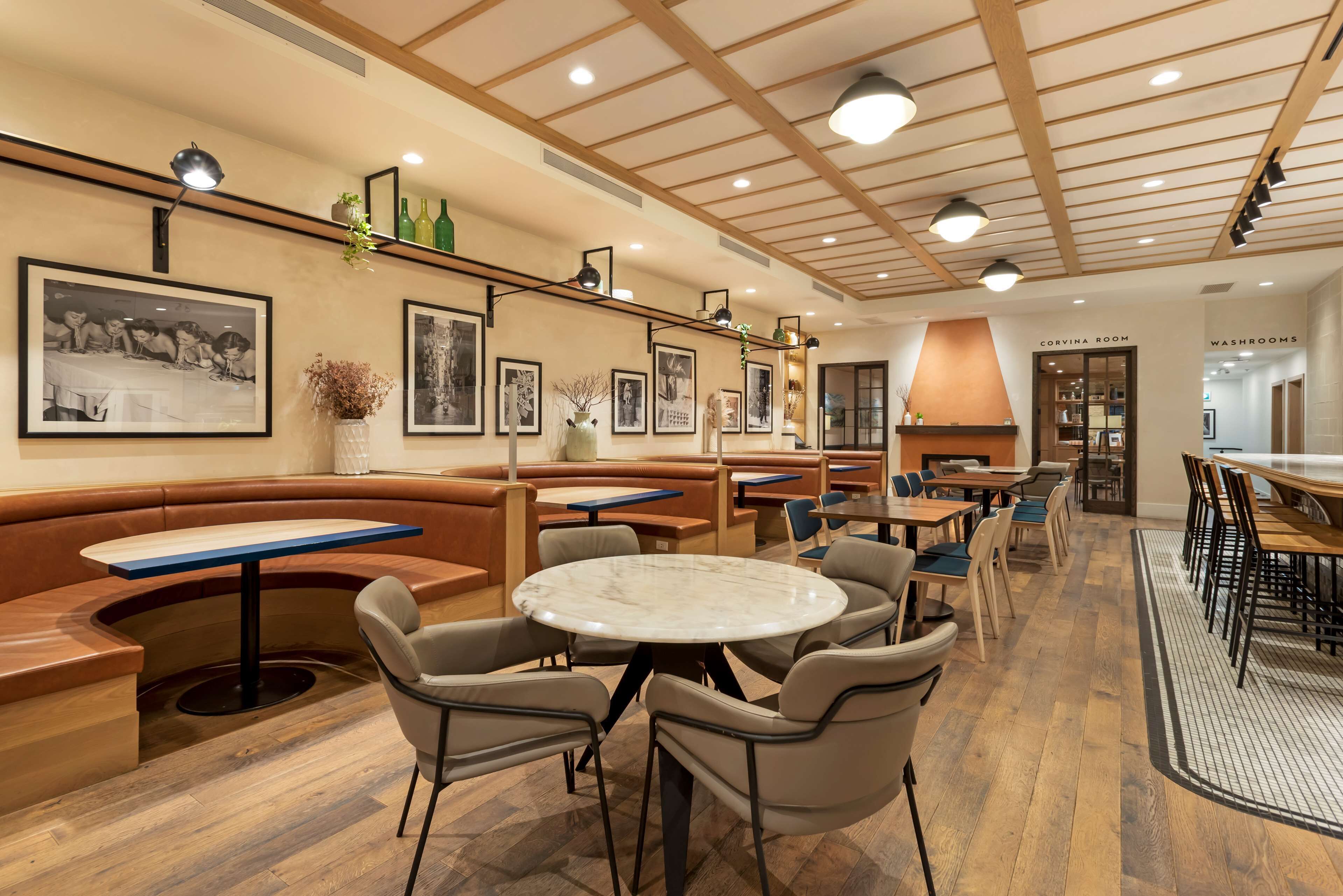 A restaurant with booths, round tables, and a variety of framed pictures on the walls.
